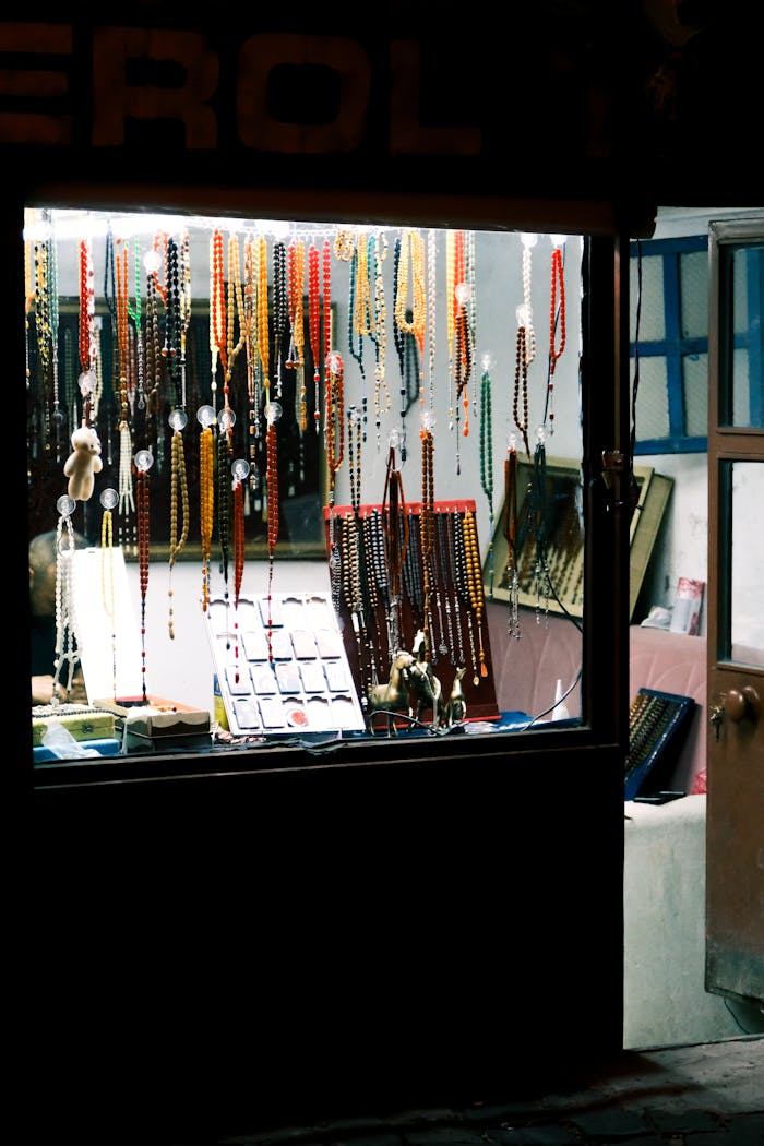 Vibrant collection of beaded jewelry showcased in a cozy, warm-lit shop window.